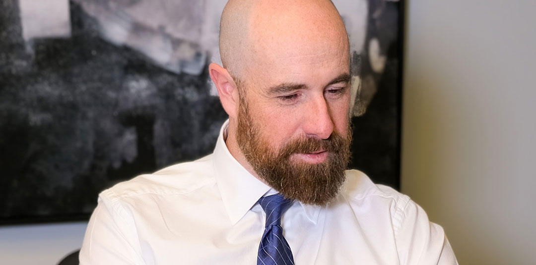 Professional man working on a laptop wearing a dress shirt and tie in a modern office setting.